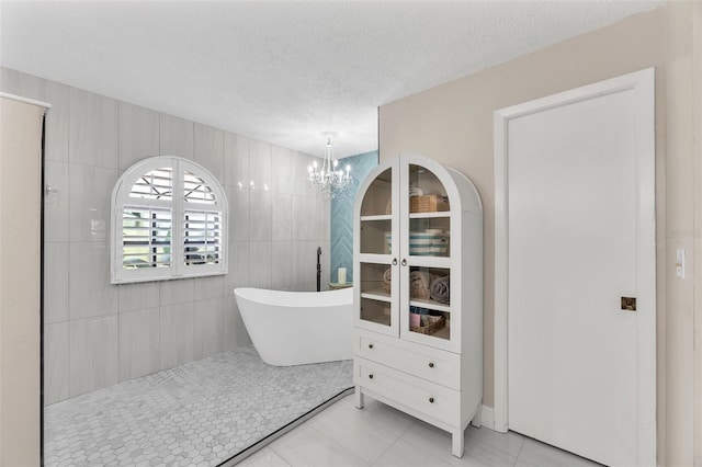 832 Birdie Way, Apollo Beach, FL 33572 - bathroom featuring a freestanding tub, a chandelier, tile patterned flooring, and a textured ceiling