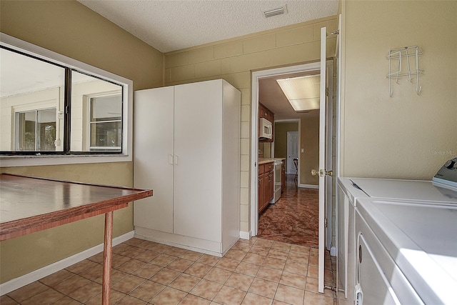 14047 Briardale Ln, Tampa, FL 33618 - laundry room featuring washer and clothes dryer, a textured ceiling, and light tile patterned floors