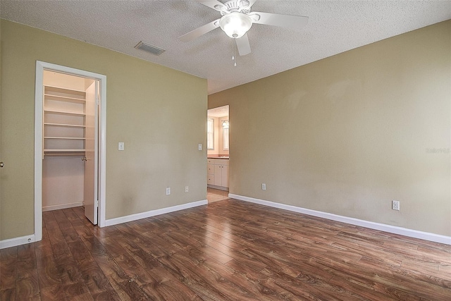 14047 Briardale Ln, Tampa, FL 33618 - unfurnished bedroom with a walk in closet, wood finished floors, a textured ceiling, a closet, and ensuite bathroom