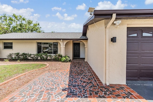 4228 Belle Isle Ct, New Port Richey, FL 34653 - doorway to property with stucco siding, an attached garage, and a shingled roof