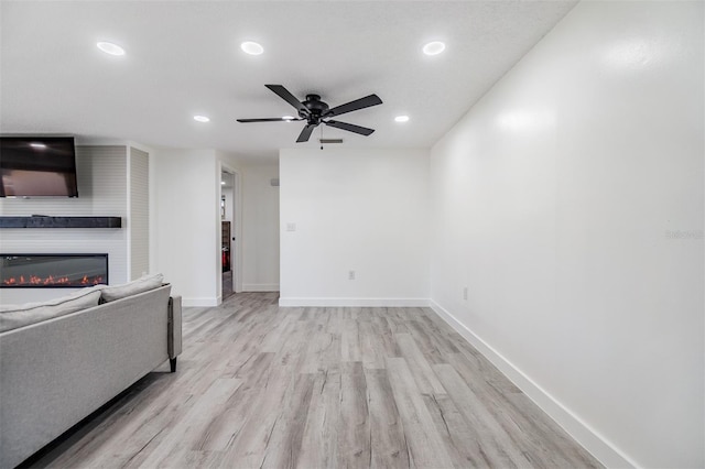 4228 Belle Isle Ct, New Port Richey, FL 34653 - unfurnished living room with recessed lighting, light wood-style flooring, a glass covered fireplace, and a ceiling fan
