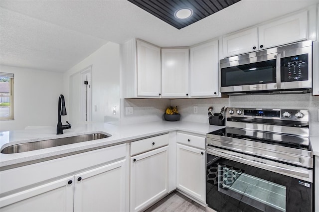 4228 Belle Isle Ct, New Port Richey, FL 34653 - kitchen featuring appliances with stainless steel finishes, light countertops, white cabinetry, light wood-style flooring, and a textured ceiling