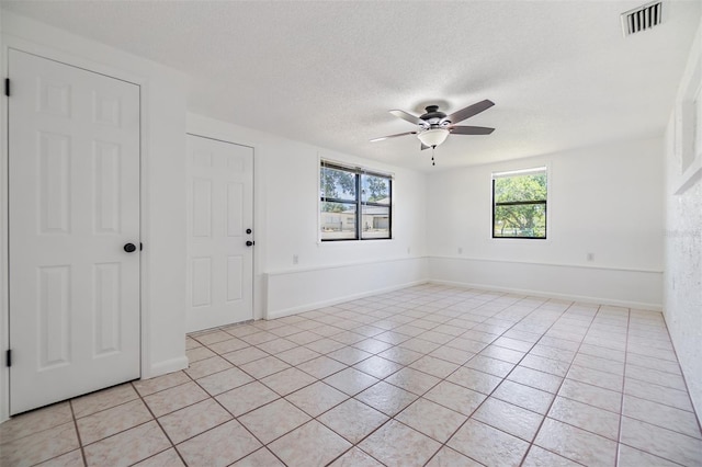 4228 Belle Isle Ct, New Port Richey, FL 34653 - empty room with plenty of natural light, ceiling fan, light tile patterned floors, and a textured ceiling