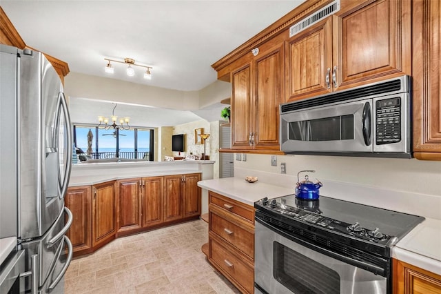 1290 Gulf Blvd Unit 702, Clearwater Beach, FL 33767 - kitchen featuring appliances with stainless steel finishes, brown cabinetry, a chandelier, and light countertops