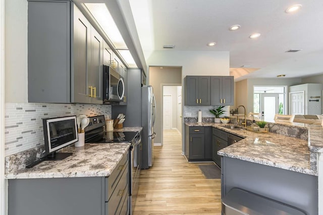 7725 235th St E, Myakka City, FL 34251 - kitchen featuring stainless steel appliances, gray cabinetry, light wood-style floors, light stone counters, and recessed lighting