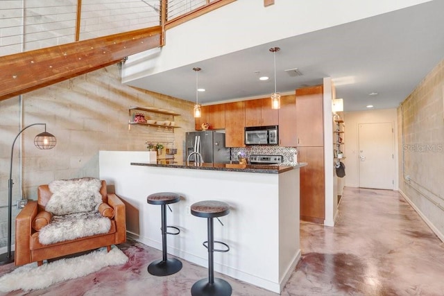 2001 E 2nd Ave Unit 37, Tampa, FL 33605 - kitchen featuring appliances with stainless steel finishes, concrete floors, a peninsula, a breakfast bar, and dark stone counters