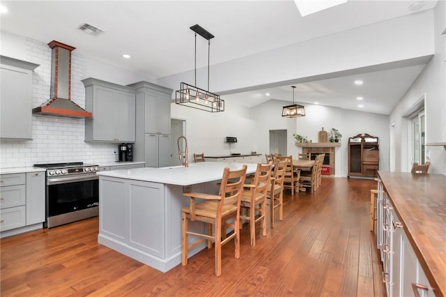 18004 Clear Lake Dr, Lutz, FL 33548 - kitchen featuring electric range, wall chimney exhaust hood, gray cabinets, wood finished floors, and vaulted ceiling