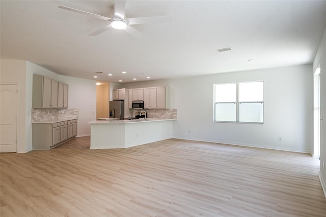 10605 Marsanne Pl, Riverview, FL 33578 - kitchen with appliances with stainless steel finishes, a peninsula, tasteful backsplash, light wood finished floors, and recessed lighting