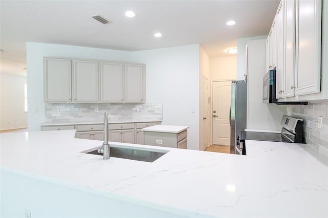 10605 Marsanne Pl, Riverview, FL 33578 - kitchen with appliances with stainless steel finishes, a center island, tasteful backsplash, light stone countertops, and recessed lighting