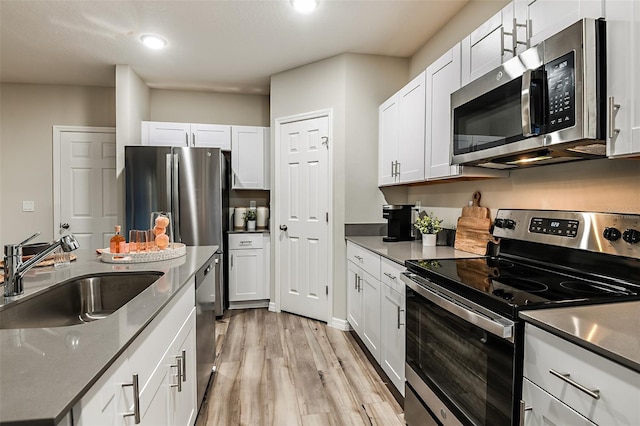 14819 Summer Branch Dr, Lithia, FL 33547 - kitchen featuring stainless steel appliances, light wood-type flooring, white cabinetry, dark countertops, and recessed lighting