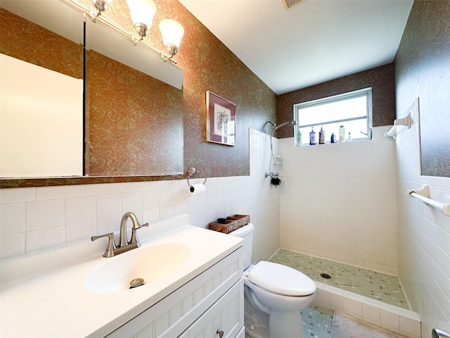 2330 Ecuadorian Way Unit 30, Clearwater, FL 33763 - bathroom with a tile shower, vanity, tile walls, wallpapered walls, and wainscoting