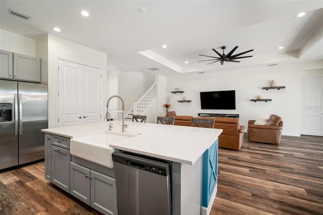 3326 Acacia Bay Ave, Wesley Chapel, FL 33543 - kitchen with appliances with stainless steel finishes, dark wood-style flooring, a tray ceiling, recessed lighting, and gray cabinetry