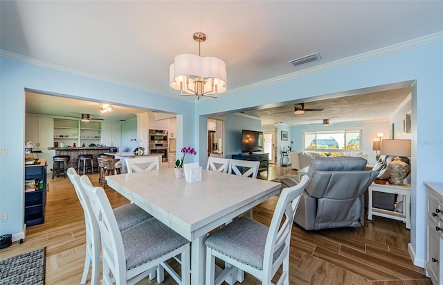 14534 Yacht Club Blvd, Seminole, FL 33776 - dining space with crown molding, a chandelier, light wood finished floors, and ceiling fan