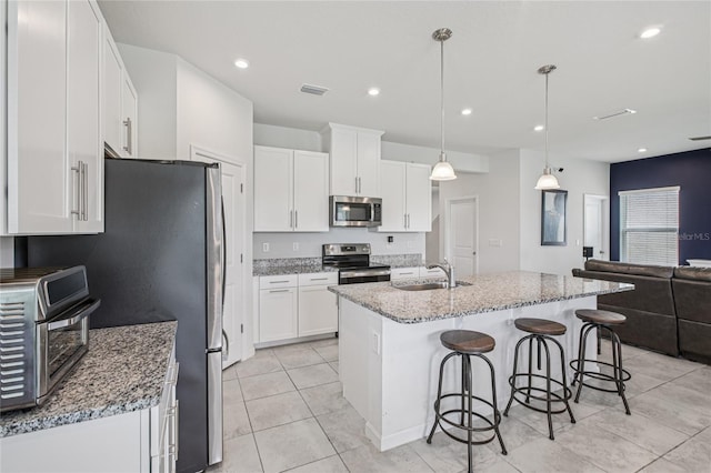10580 Gliding Eagle Way, Land O Lakes, FL 34638 - kitchen with appliances with stainless steel finishes, open floor plan, white cabinets, a breakfast bar, and light tile patterned floors
