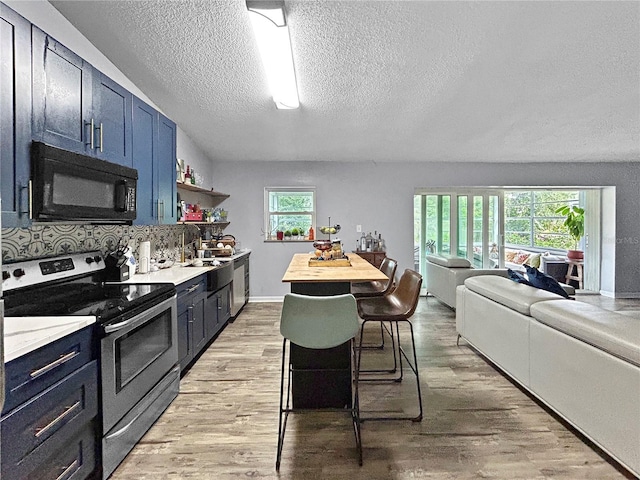 1609 Haven Bnd, Tampa, FL 33613 - kitchen with stainless steel electric range oven, black microwave, a textured ceiling, blue cabinets, and light wood-type flooring