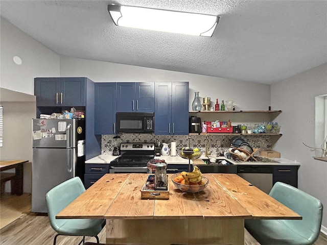 1609 Haven Bnd, Tampa, FL 33613 - kitchen with stainless steel appliances, blue cabinetry, light wood-style flooring, a kitchen breakfast bar, and vaulted ceiling