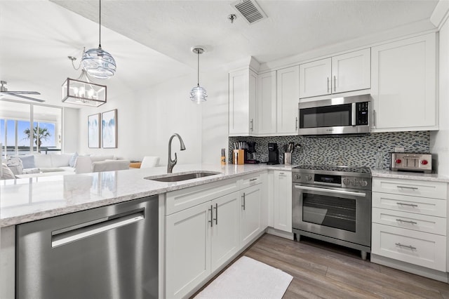 615 Dream Island Pl Unit 210, Longboat Key, FL 34228 - kitchen featuring appliances with stainless steel finishes, tasteful backsplash, white cabinets, open floor plan, and wood finished floors