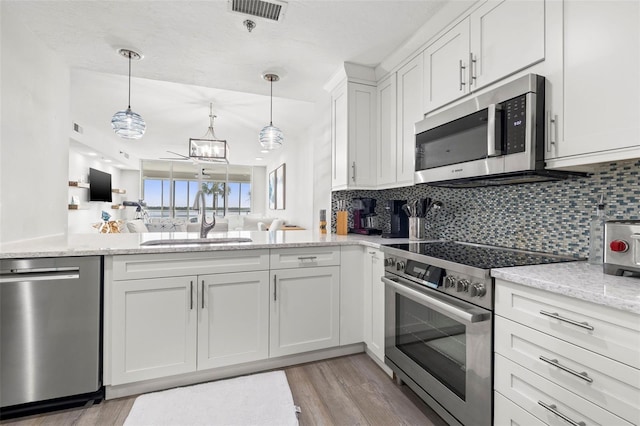 615 Dream Island Pl Unit 210, Longboat Key, FL 34228 - kitchen with appliances with stainless steel finishes, backsplash, white cabinetry, and light wood-type flooring