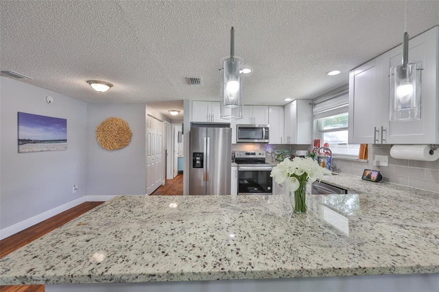 540 Firefly Ln, Apollo Beach, FL 33572 - kitchen with appliances with stainless steel finishes, light stone countertops, dark wood-style floors, white cabinets, and a textured ceiling