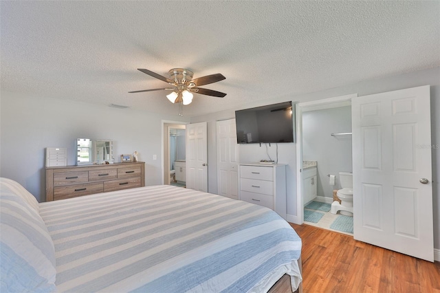 540 Firefly Ln, Apollo Beach, FL 33572 - bedroom featuring light wood-style floors, a textured ceiling, connected bathroom, and a ceiling fan