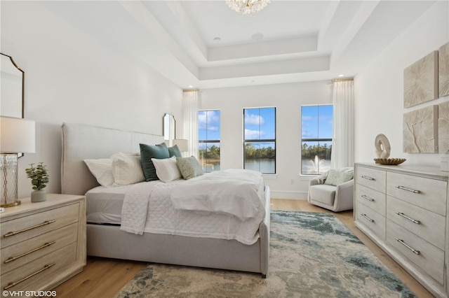 19781 Marino Lake Cir Unit 202, Miromar Lakes, FL 33913 - bedroom with light wood-type flooring, a tray ceiling, a water view, and a chandelier