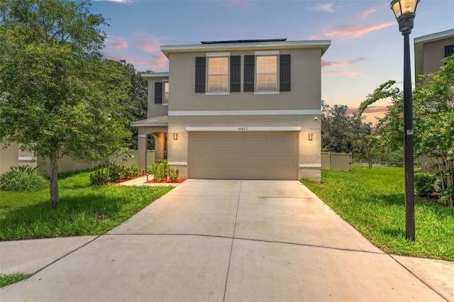 10823 Trailing Vine Dr, Tampa, FL 33610 - traditional-style home with stucco siding, concrete driveway, roof mounted solar panels, a garage, and a front yard
