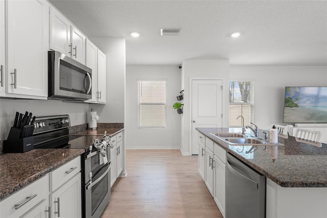 10823 Trailing Vine Dr, Tampa, FL 33610 - kitchen featuring appliances with stainless steel finishes, light wood-type flooring, white cabinets, a center island with sink, and recessed lighting