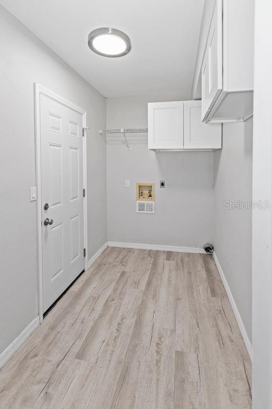 7322 Ellis Ln, Port Charlotte, FL 33981 - washroom with electric dryer hookup, light wood-style floors, cabinet space, and hookup for a washing machine