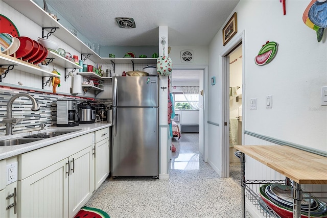 505 67th Ave Unit 11, St Pete Beach, FL 33706 - kitchen with freestanding refrigerator, open shelves, dark aggregate flooring, white cabinetry, and light countertops