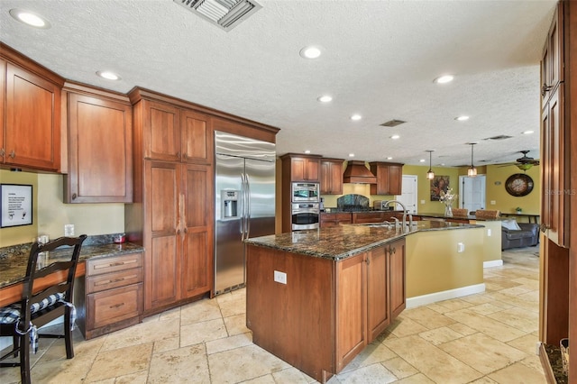 16205 Sentry Woods Ct, Odessa, FL 33556 - kitchen featuring stainless steel appliances, a kitchen island with sink, recessed lighting, custom range hood, and a textured ceiling