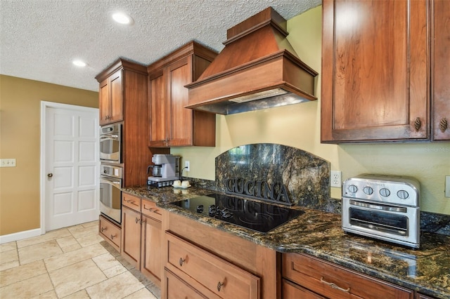 16205 Sentry Woods Ct, Odessa, FL 33556 - kitchen featuring premium range hood, black electric cooktop, dark stone counters, brown cabinetry, and a textured ceiling