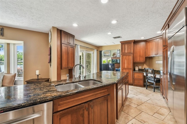 16205 Sentry Woods Ct, Odessa, FL 33556 - kitchen with appliances with stainless steel finishes, recessed lighting, a textured ceiling, brown cabinets, and dark stone counters