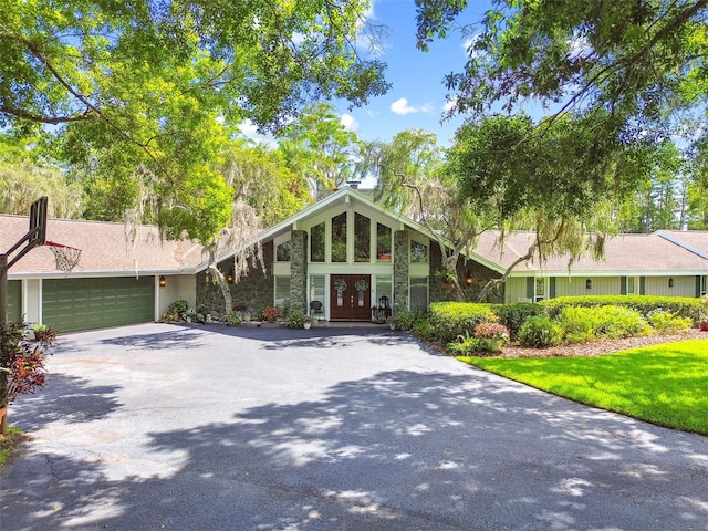 16205 Sentry Woods Ct, Odessa, FL 33556 - mid-century modern home with driveway, a garage, french doors, and stone siding