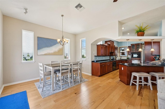 6543 Louise Ct, Hudson, FL 34667 - kitchen featuring oven, dark countertops, light wood-type flooring, a breakfast bar area, and arched walkways
