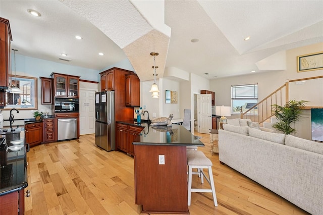 6543 Louise Ct, Hudson, FL 34667 - kitchen featuring stainless steel appliances, a peninsula, dark countertops, a kitchen breakfast bar, and light wood-style floors