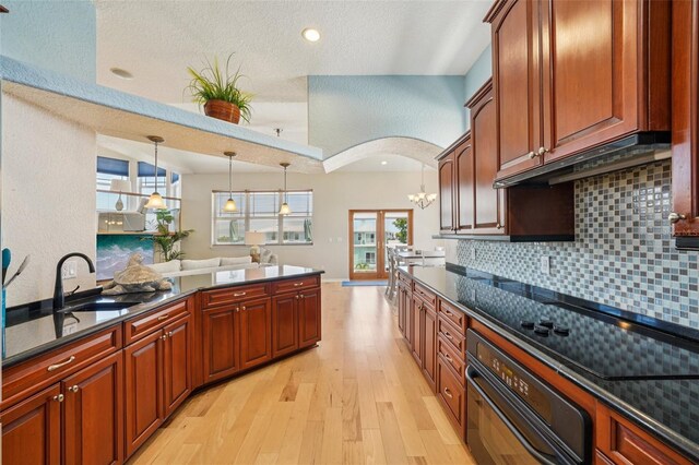 6543 Louise Ct, Hudson, FL 34667 - kitchen featuring light wood-style flooring, tasteful backsplash, oven, hanging light fixtures, and arched walkways