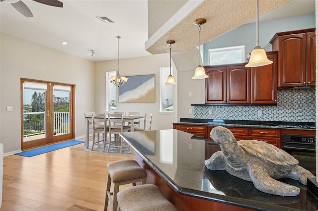 6543 Louise Ct, Hudson, FL 34667 - kitchen featuring black oven, light wood-style floors, pendant lighting, and a kitchen breakfast bar