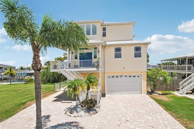 6543 Louise Ct, Hudson, FL 34667 - coastal home with stairway, an attached garage, decorative driveway, a metal roof, and a porch