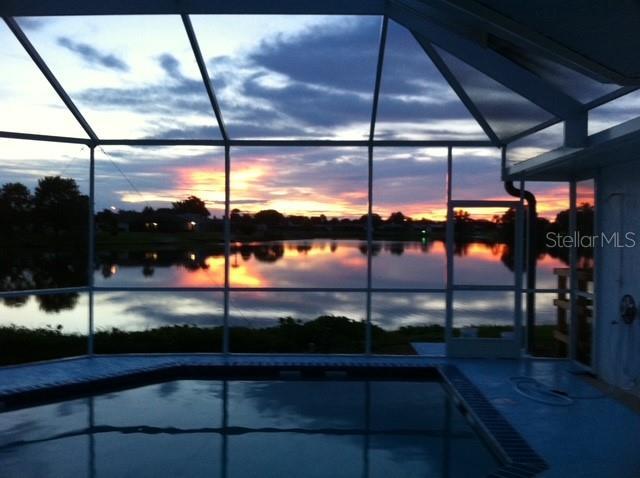 9619 Towanda Ln, Port Richey, FL 34668 - pool at dusk with a lanai, a water view, and an outdoor pool