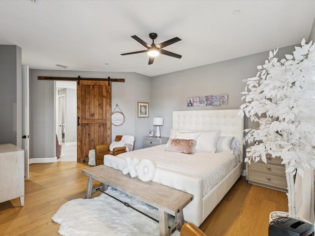 1340 Bayshore Blvd Unit 502, Dunedin, FL 34698 - bedroom with a barn door, light wood-style flooring, and ceiling fan