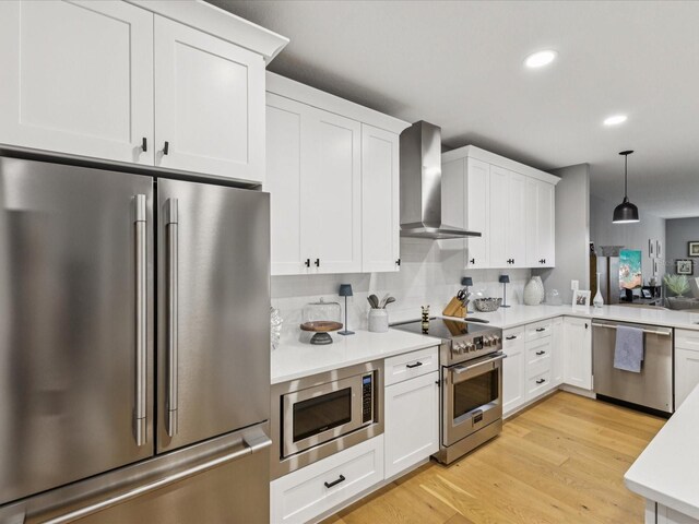 1340 Bayshore Blvd Unit 502, Dunedin, FL 34698 - kitchen with appliances with stainless steel finishes, wall chimney exhaust hood, light countertops, light wood-style floors, and white cabinetry