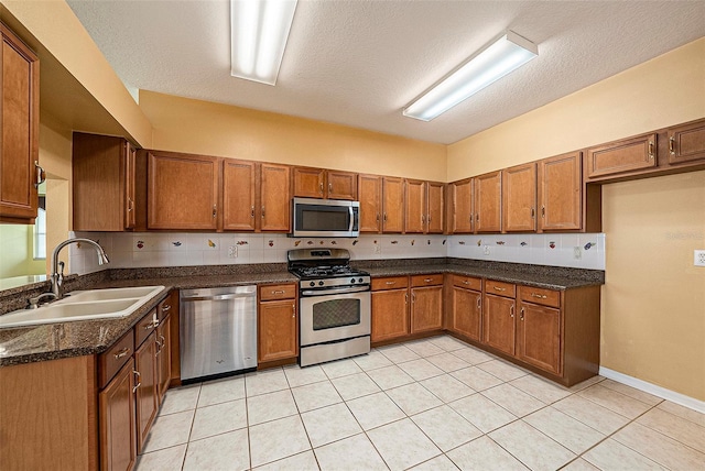 1914 Sassafras Dr, Wesley Chapel, FL 33543 - kitchen with appliances with stainless steel finishes, brown cabinets, light tile patterned floors, dark stone countertops, and a textured ceiling
