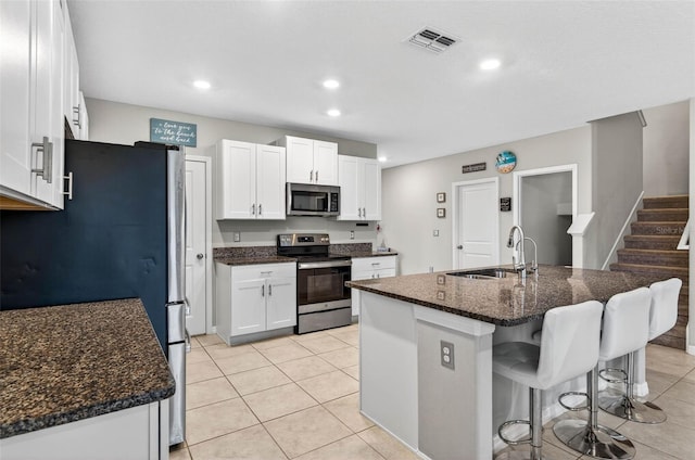 12835 Wildflower Meadow Dr, Riverview, FL 33579 - kitchen with appliances with stainless steel finishes, a breakfast bar area, white cabinetry, recessed lighting, and an island with sink