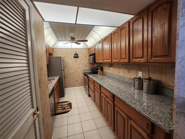 400 64th Ave Unit 1105, St Pete Beach, FL 33706 - kitchen featuring appliances with stainless steel finishes, ceiling fan, light tile patterned floors, vaulted ceiling, and dark stone counters