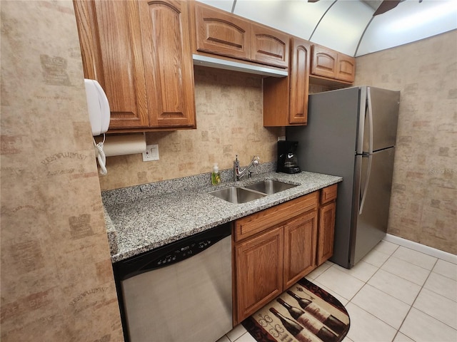 400 64th Ave Unit 1105, St Pete Beach, FL 33706 - kitchen featuring appliances with stainless steel finishes, light stone countertops, light tile patterned floors, and brown cabinets