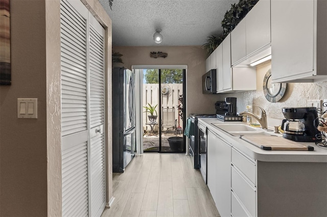 2922 60th St W, Bradenton, FL 34209 - kitchen featuring stainless steel appliances, light countertops, white cabinetry, light wood-type flooring, and a textured ceiling