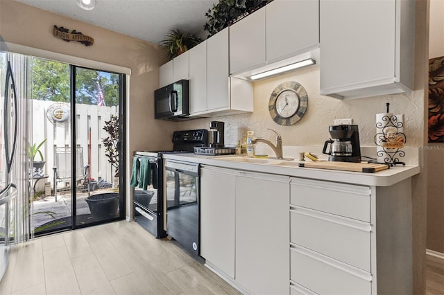 2922 60th St W, Bradenton, FL 34209 - kitchen with black appliances, light countertops, white cabinets, and light wood-style floors