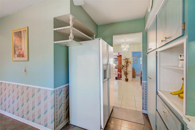 11082 90th Ter, Seminole, FL 33772 - kitchen with white fridge with ice dispenser, wainscoting, a chandelier, and light tile patterned floors