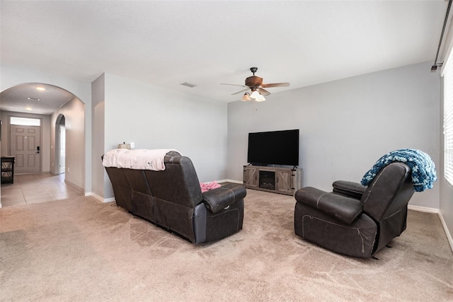 15406 Gopher Trop Pl, Sun City Center, FL 33573 - living room featuring arched walkways, light carpet, ceiling fan, and light tile patterned flooring