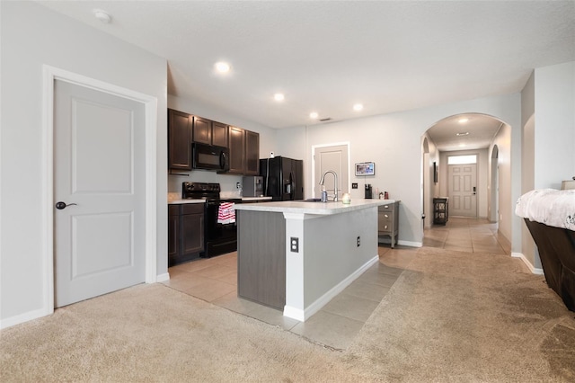 15406 Gopher Trop Pl, Sun City Center, FL 33573 - kitchen featuring black appliances, light tile patterned floors, arched walkways, light countertops, and a kitchen island with sink